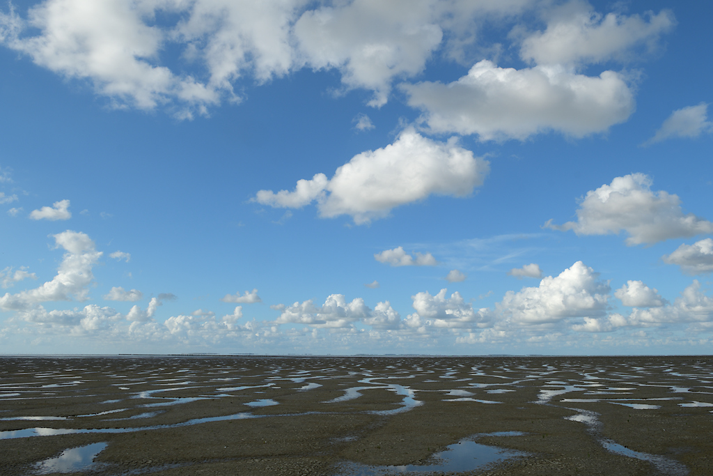 Weerspiegeling van de lucht in plassen op het slik